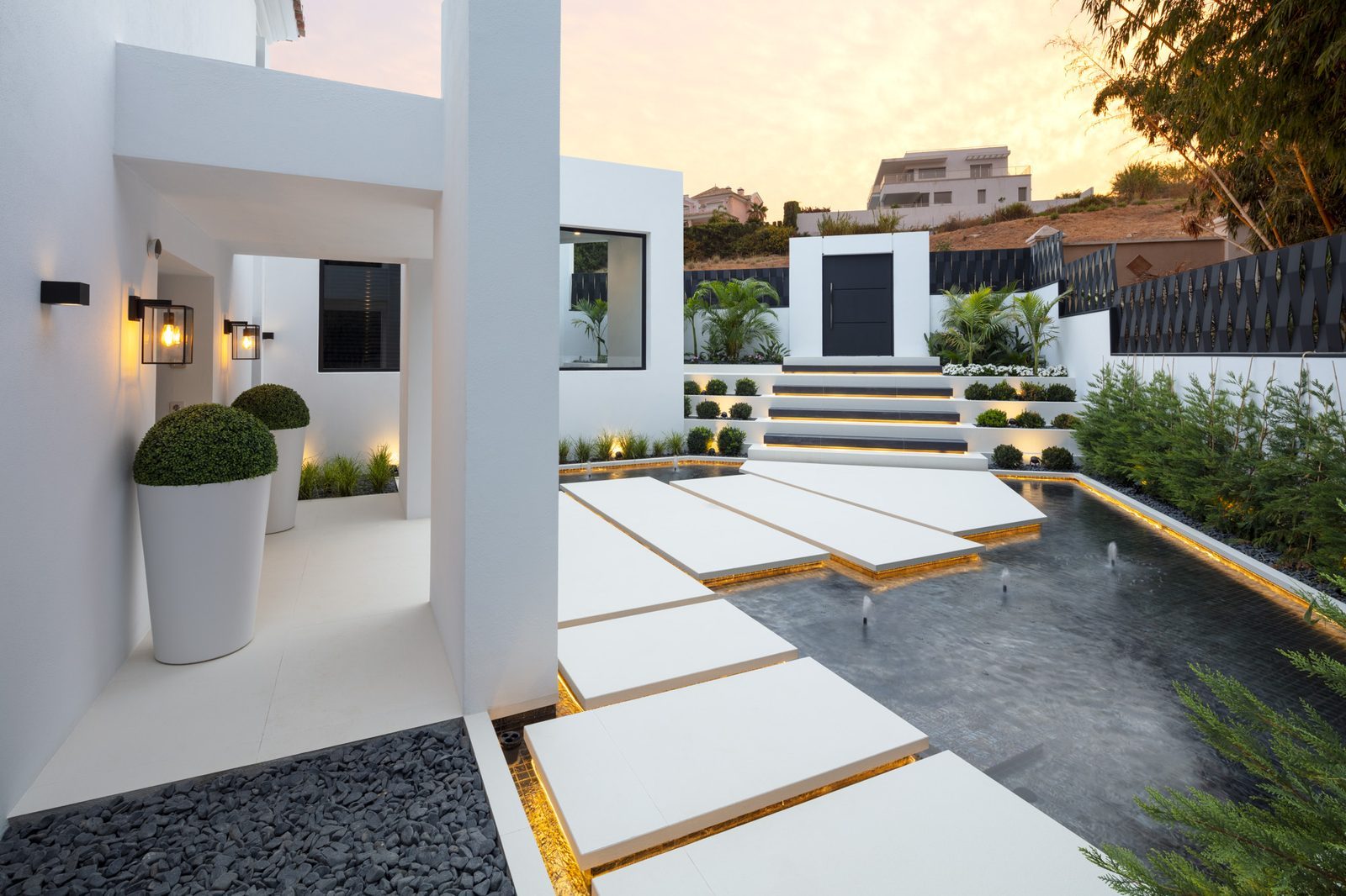 Modern villa courtyard with an illuminated pool, stepping stones and landscaped entrance of a 5-bedroom villa in Málaga - The Estates
