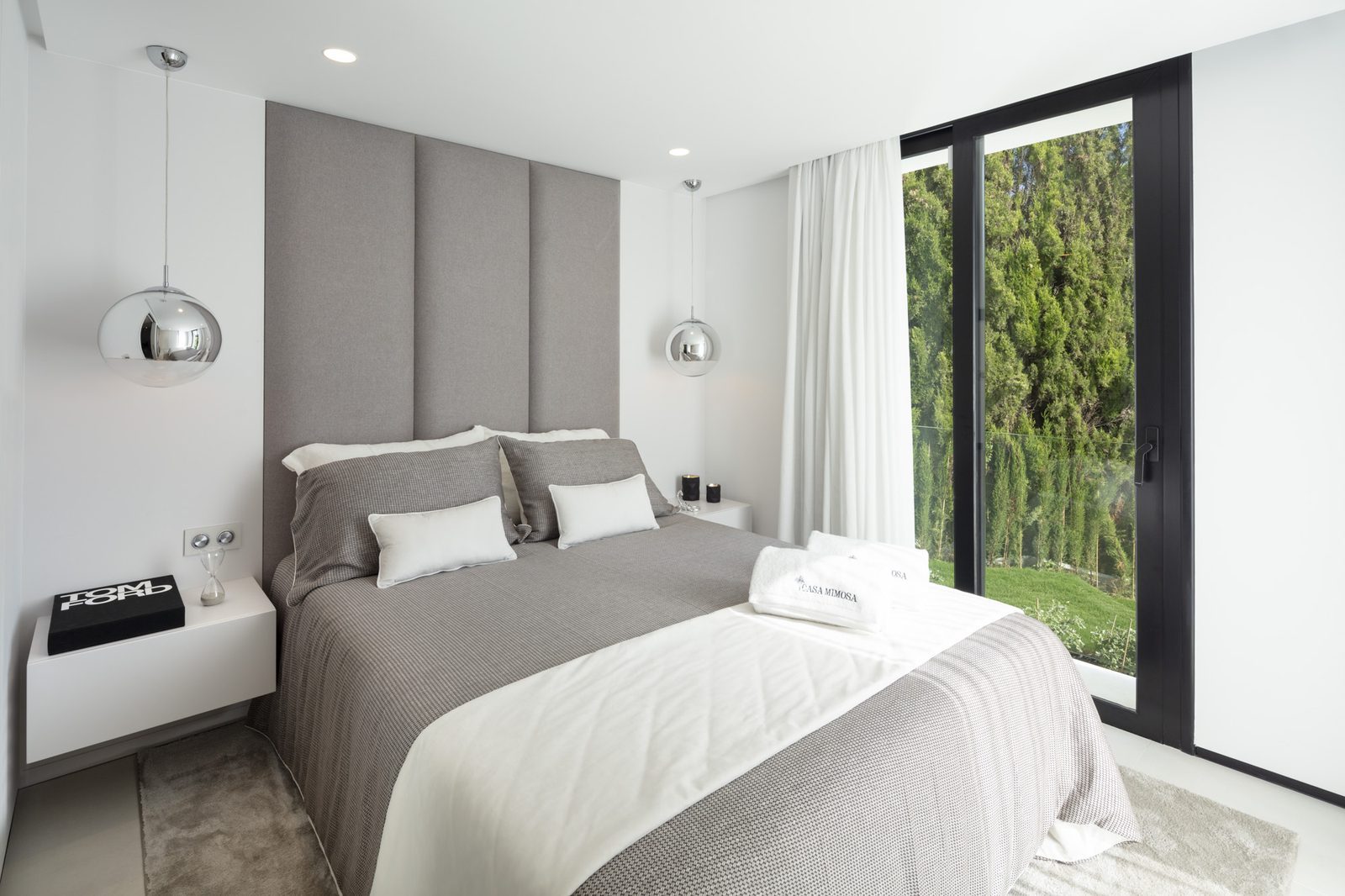 Modern double bedroom with grey bedding, pendant lights and floor-to-ceiling garden views of a 5-bedroom villa in Málaga - The Estates