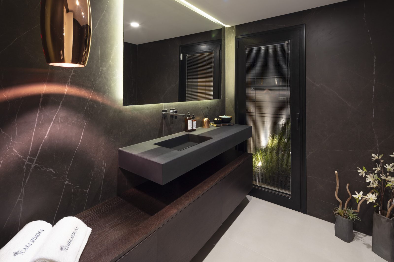 Modern dark marble bathroom with floating vanity and illuminated mirror in a 5-bedroom villa in Málaga - The Estates