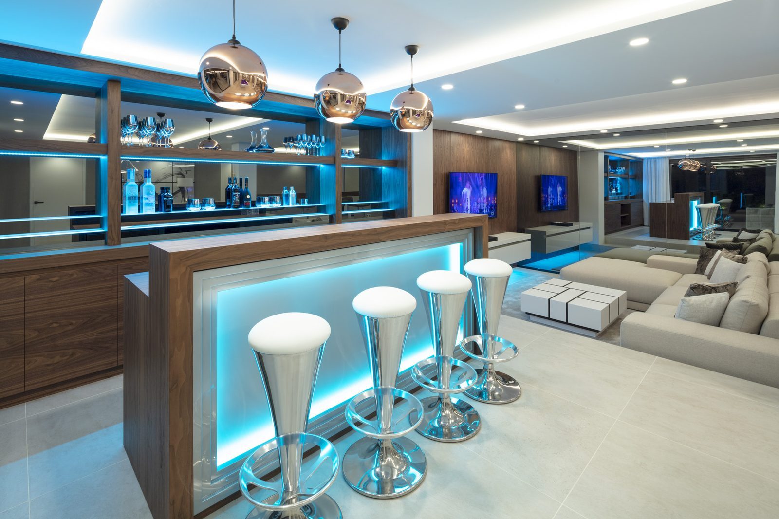 Modern home bar and lounge with illuminated bar stools, shelving and pendant lights in a 5-bedroom villa in Málaga - The Estates