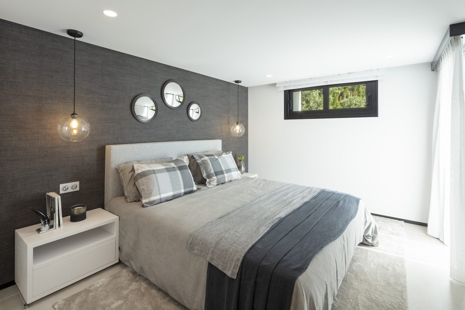 Stylish bedroom with a double bed, pendant lights and round mirrors in a 5-bedroom villa in Málaga - The Estates