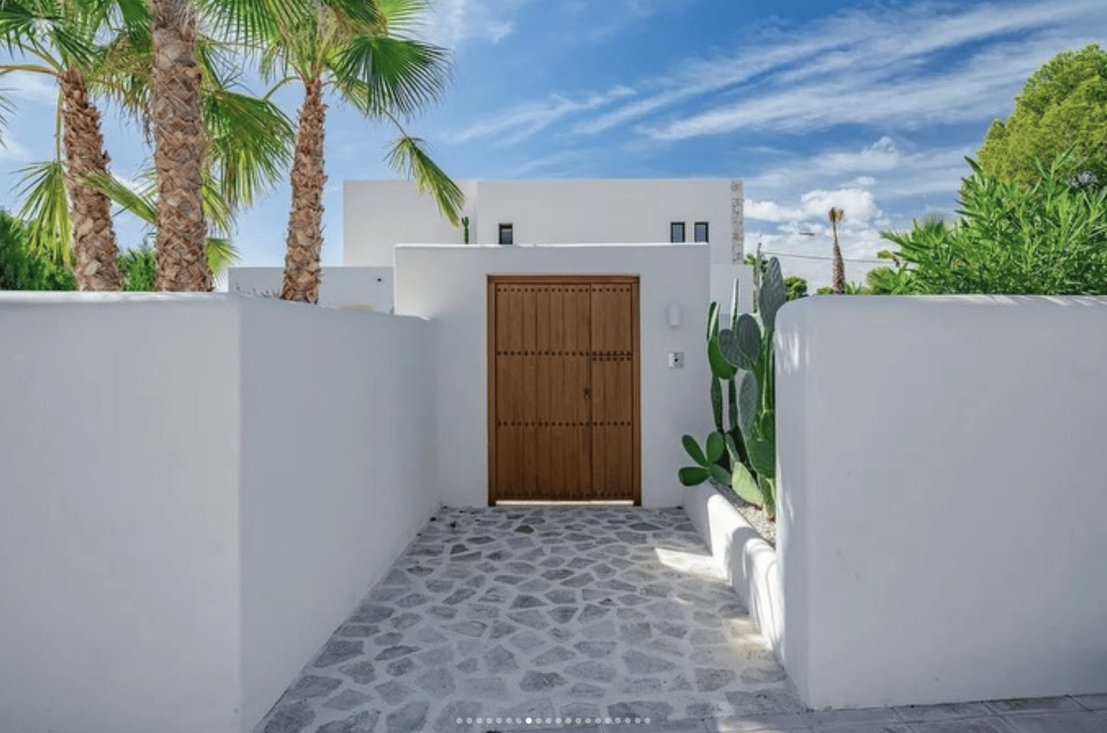 A modern entrance with palm trees and a wooden door of a 5-bedroom villa in Benissa - The Estates
