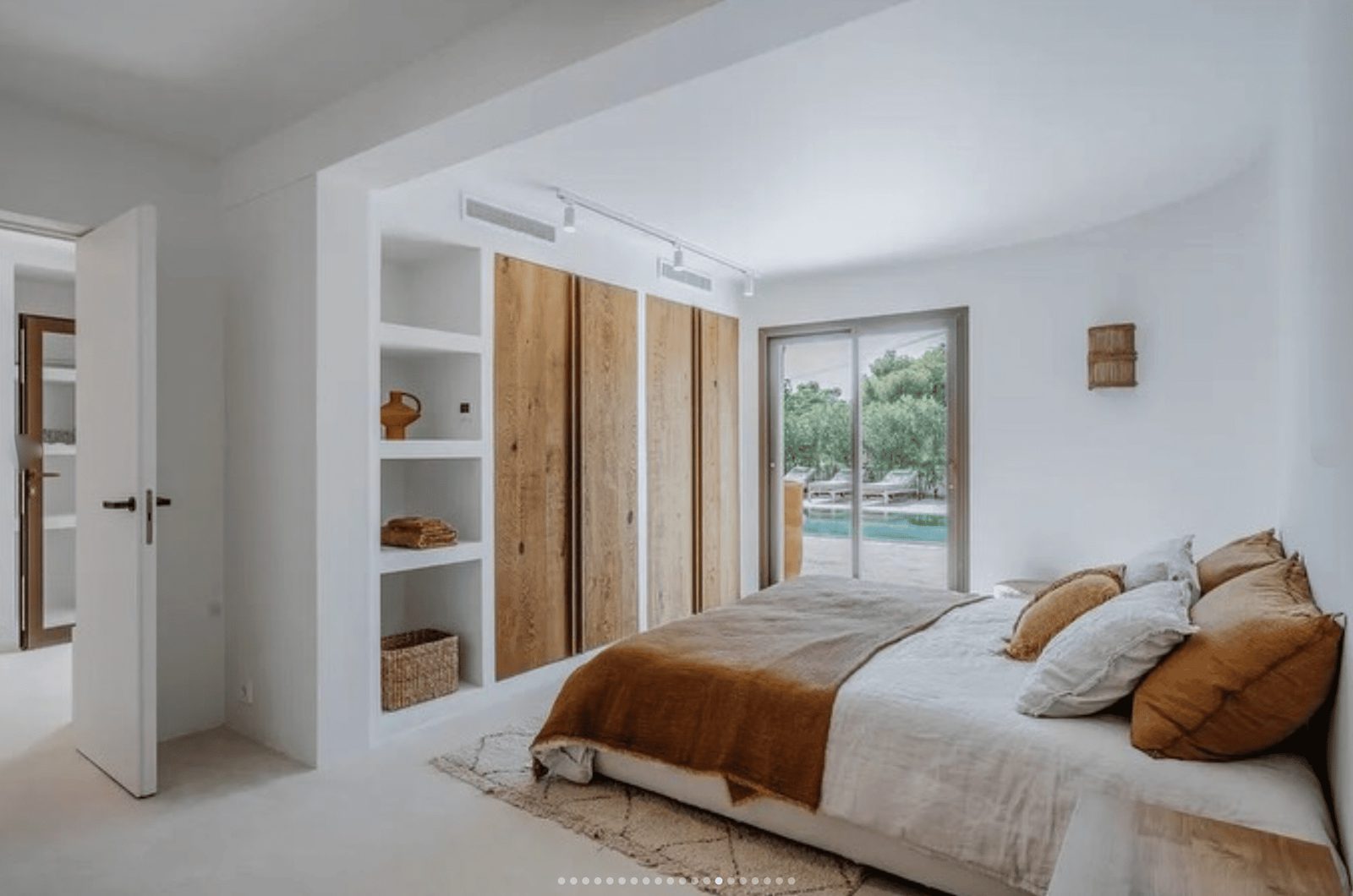 A bright bedroom with built-in storage and views of the pool in a 5-bedroom villa in Benissa - The Estates