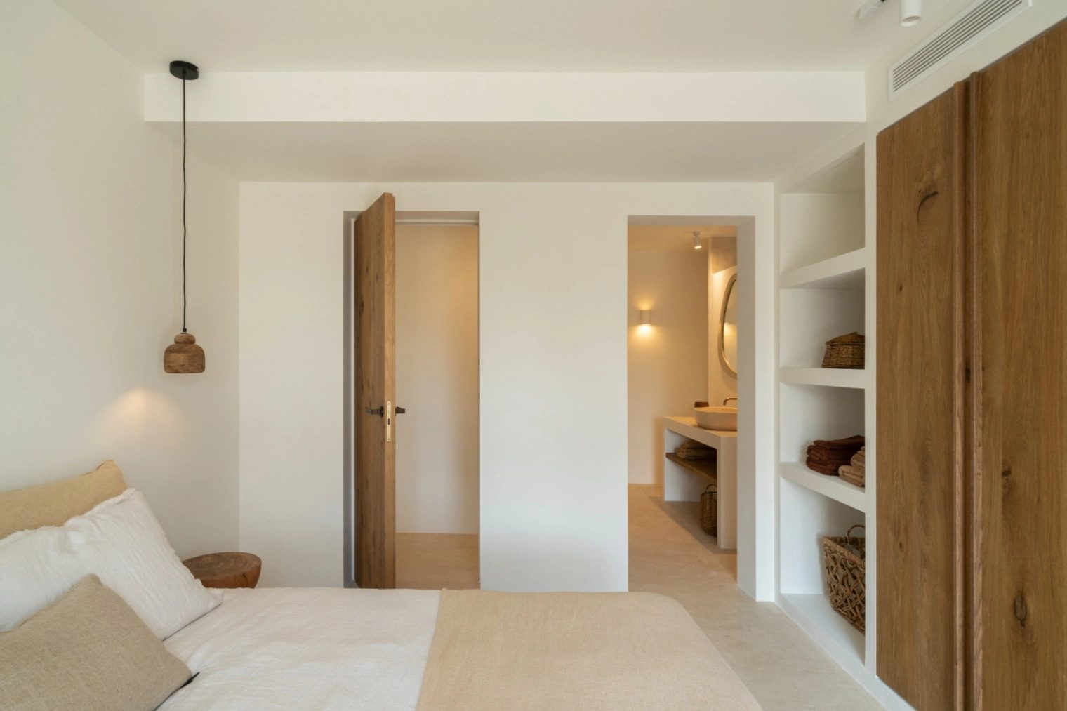 Stylish bedroom interior with built-in storage and doorway to an en-suite bathroom in a 5-bedroom villa in Benissa - The Estates