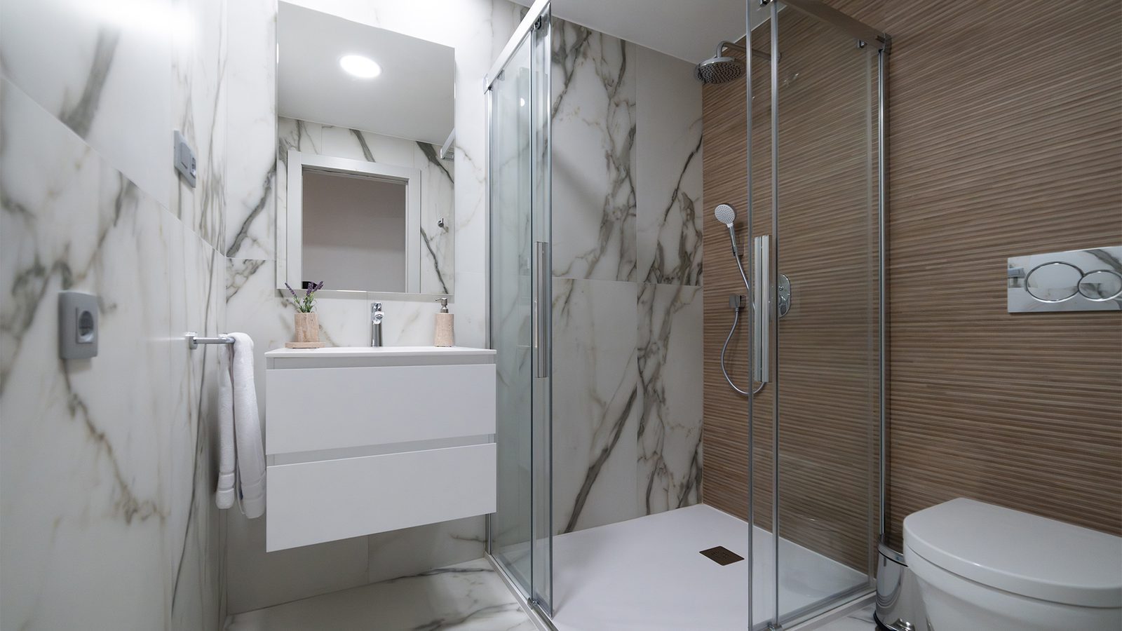 Modern bathroom with walk-in glass shower, marble-effect tiles and wall-mounted vanity in a 2-bedroom apartment in Benidorm - The Estates
