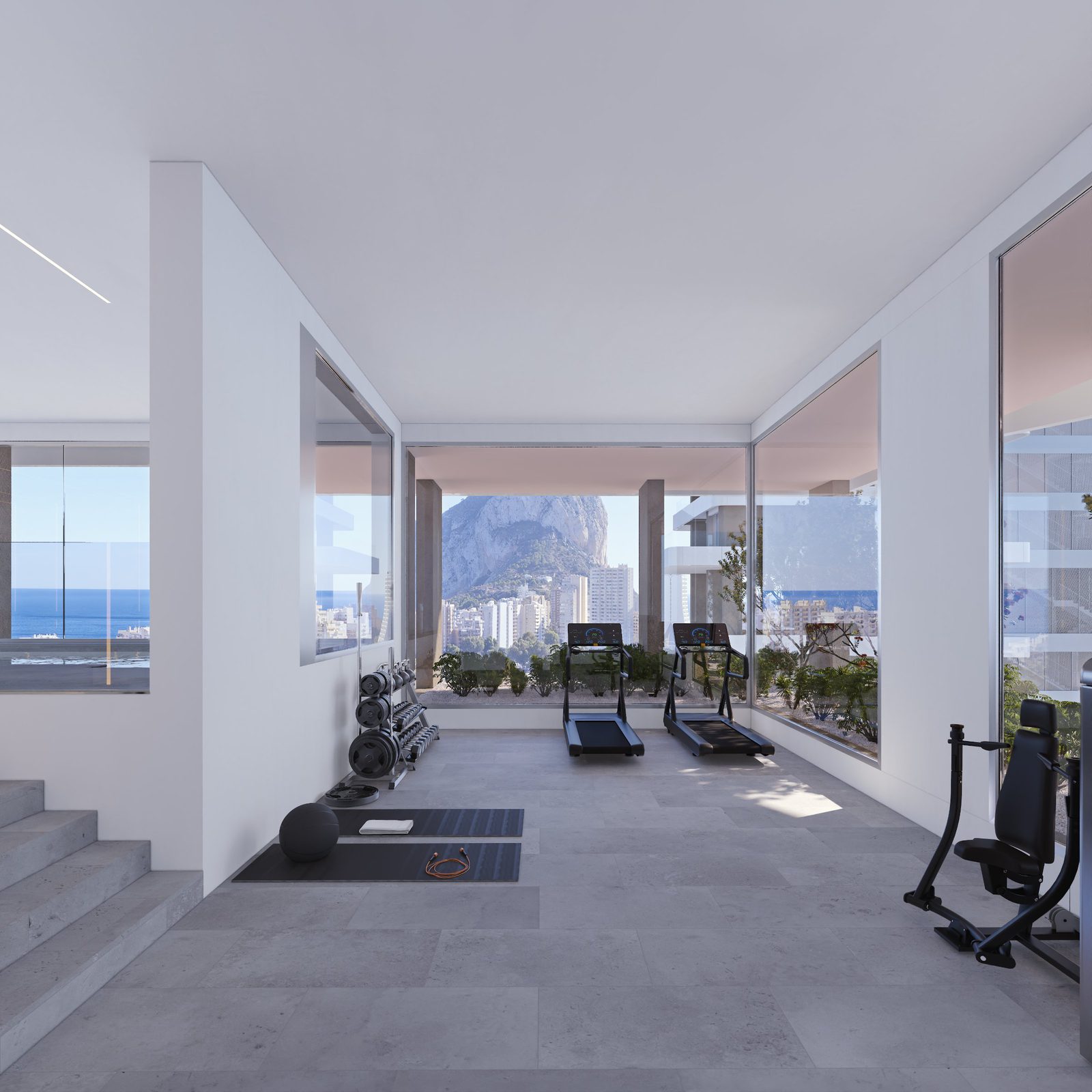 A modern gym with weights and treadmills, overlooking the sea and mountains in a 2-bedroom apartment in Calpe - The Estates