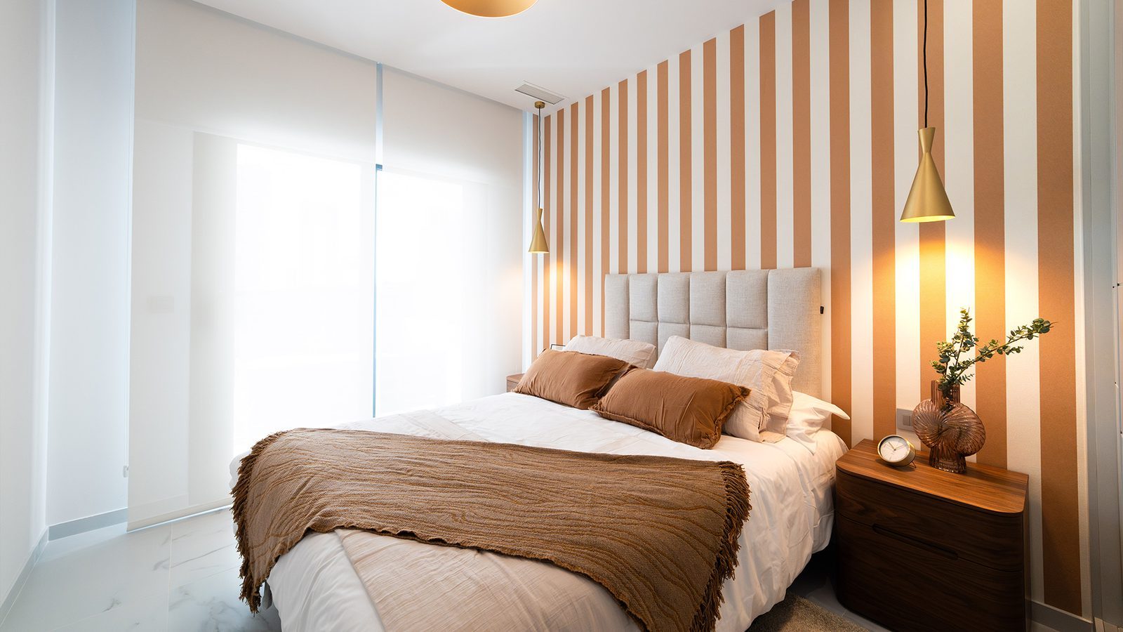 Master bedroom with king-size bed, striped accent wall and bedside tables in a 2-bedroom apartment in Benidorm - The Estates
