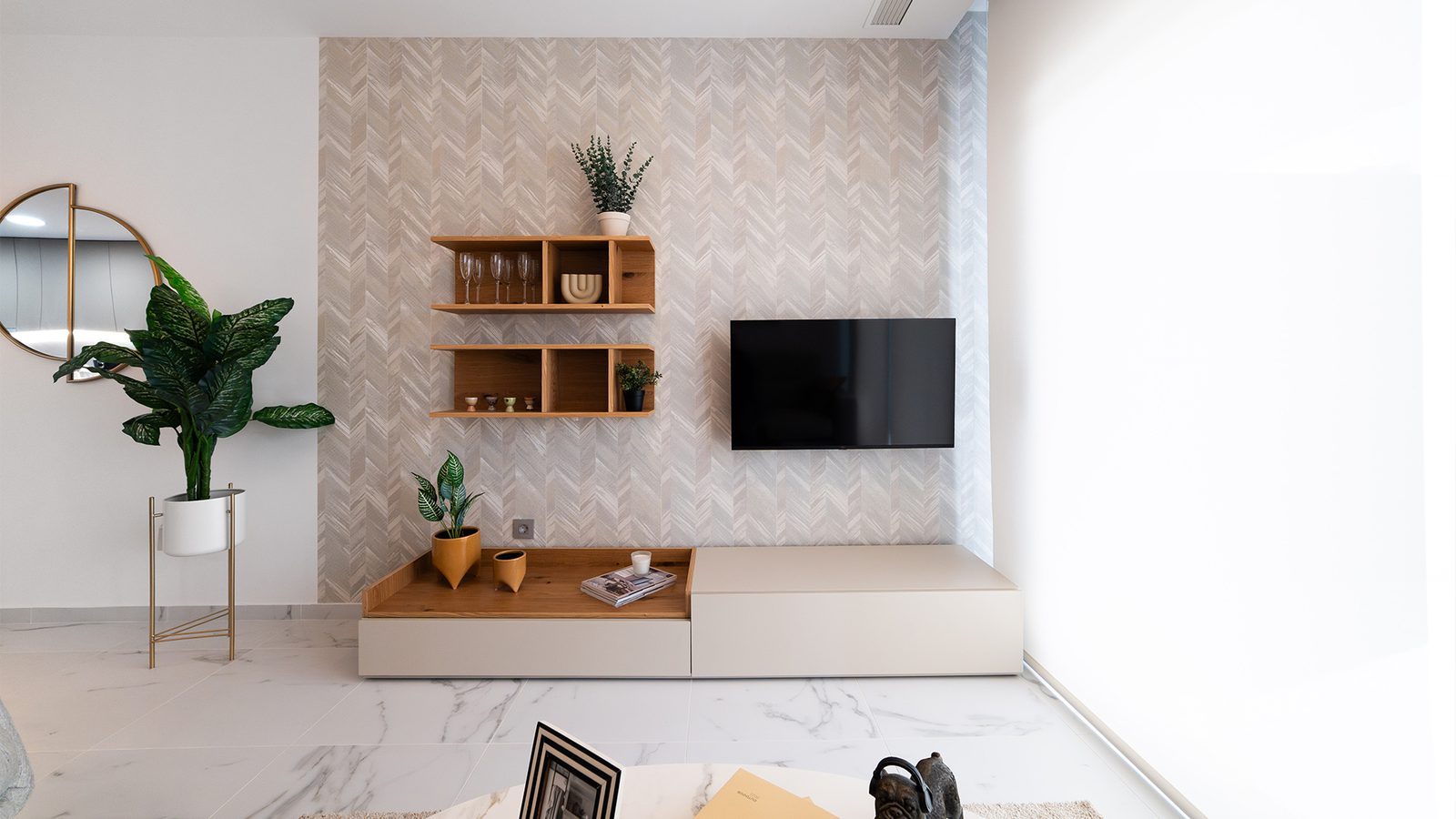 Modern living room with wall-mounted TV, patterned feature wall and shelving in a 2-bedroom apartment in Benidorm - The Estates