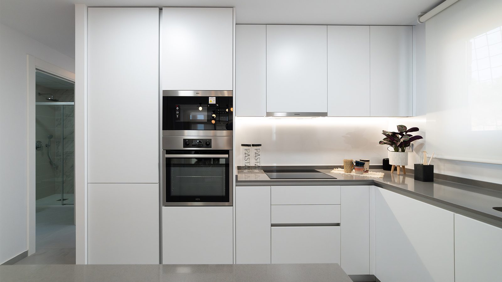 Modern white fitted kitchen with integrated appliances of a 2-bedroom apartment in Benidorm - The Estates
