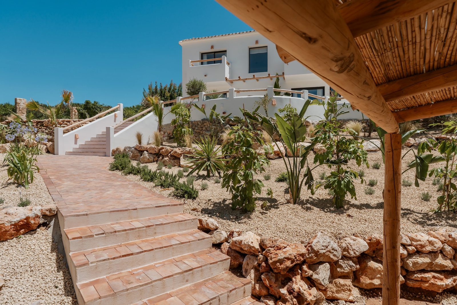 Exterior view of a 4-bedroom villa in Javea with lush gardens and stone steps - The Estates