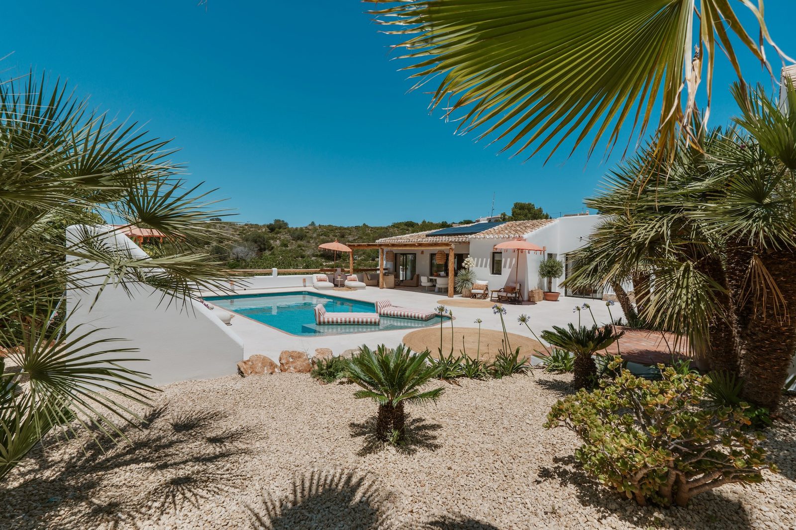 A beautiful pool and villa framed by palm trees in Javea - The Estates