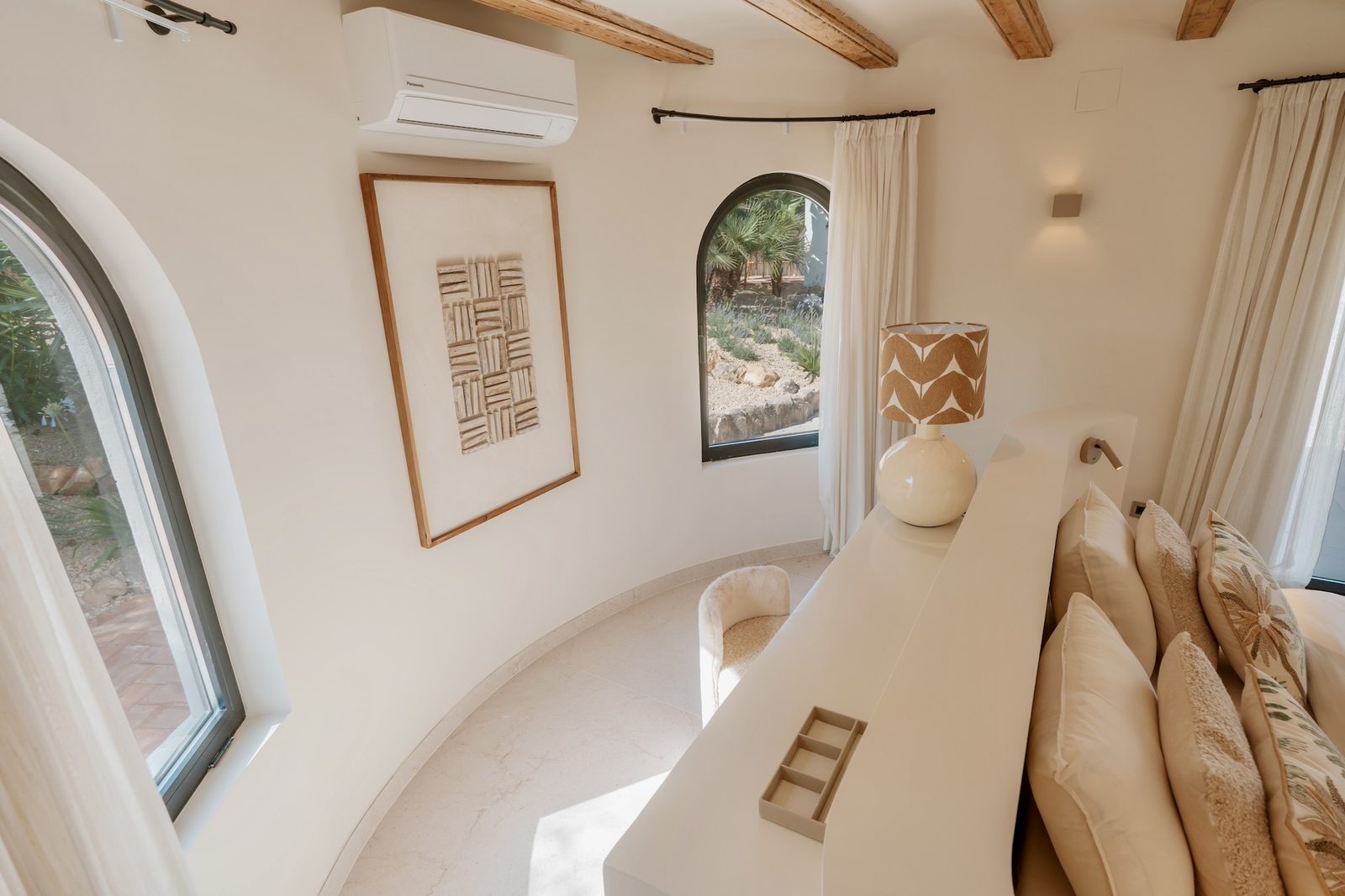 A bright, stylish bedroom interior with arched windows and a decorative accent wall - The Estates