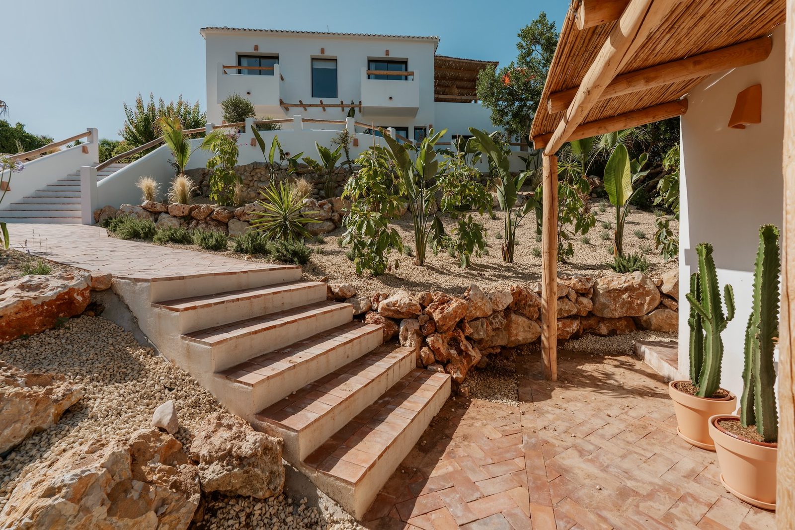 Exterior view of a 4-bedroom villa in Javea with lush gardens and stone steps - The Estates