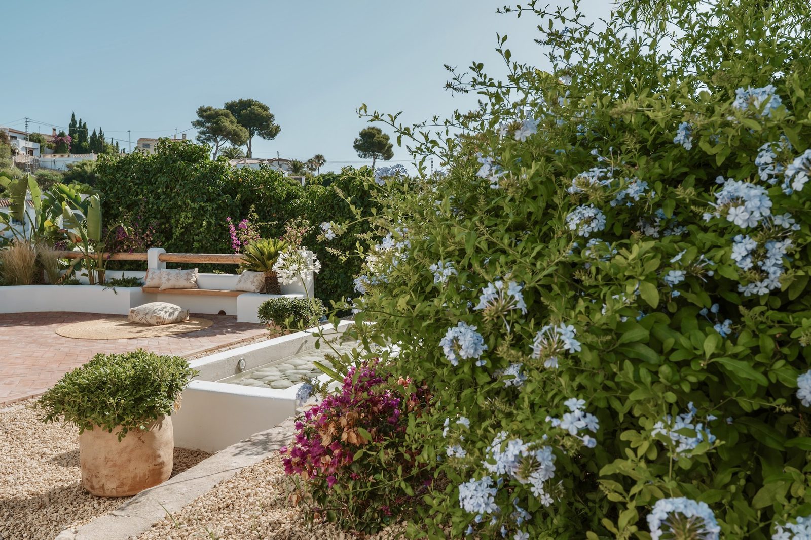 Lush garden with flowering shrubs and a seating area at a 4-bedroom villa in Javea - The Estates
