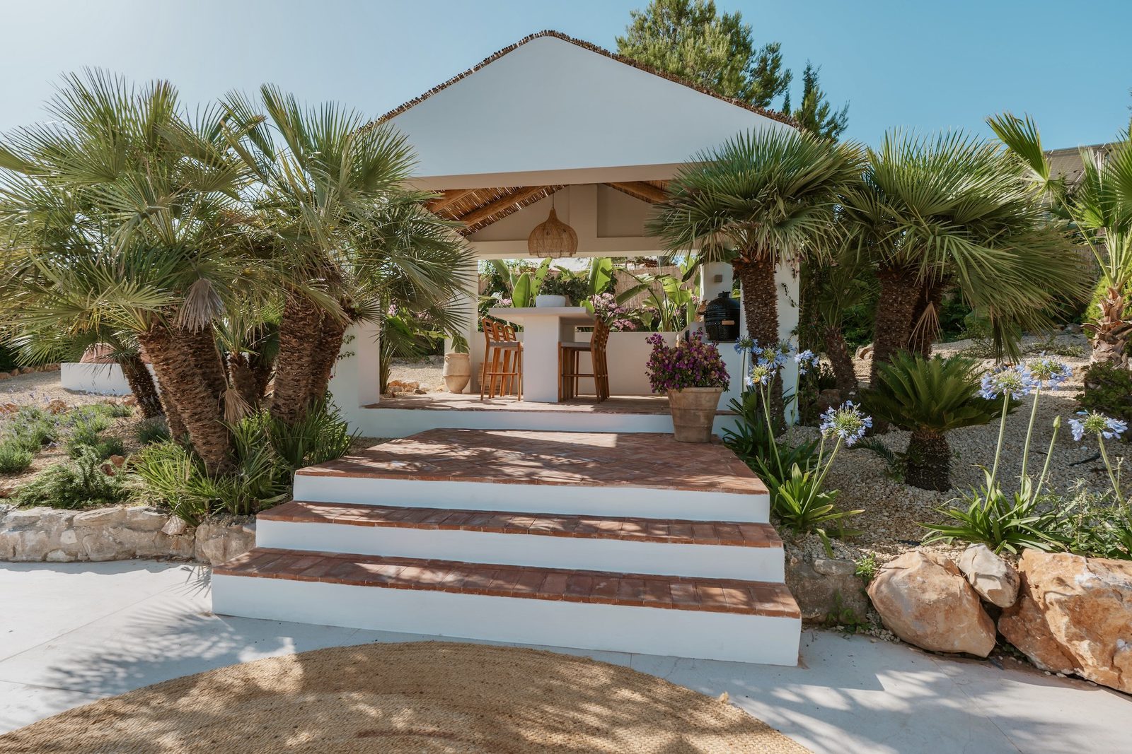 Outdoor dining area with palm trees and flowers at a 4-bedroom villa in Javea - The Estates