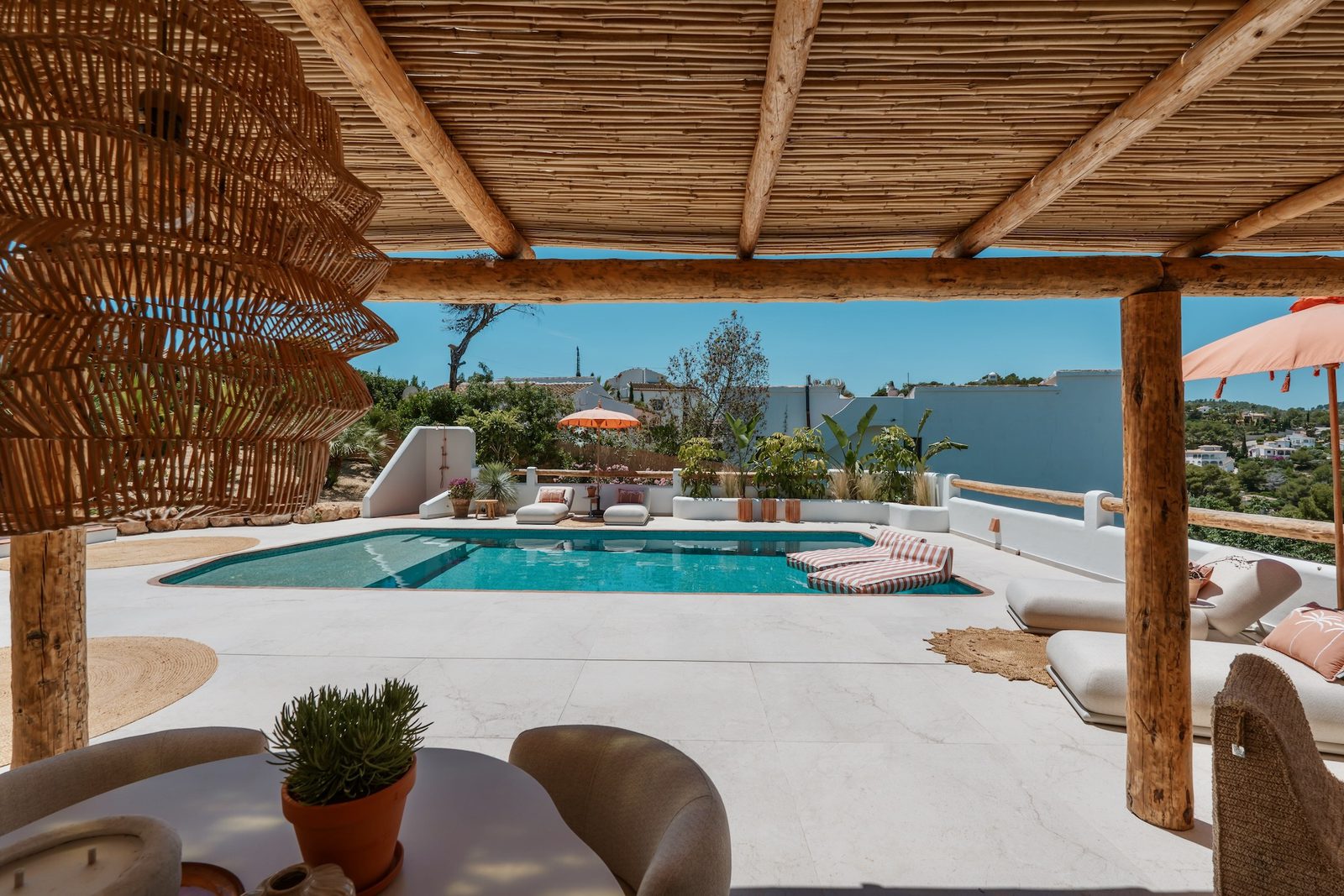 A stylish pool area with a pergola and outdoor seating on a 4-bedroom villa in Javea - The Estates