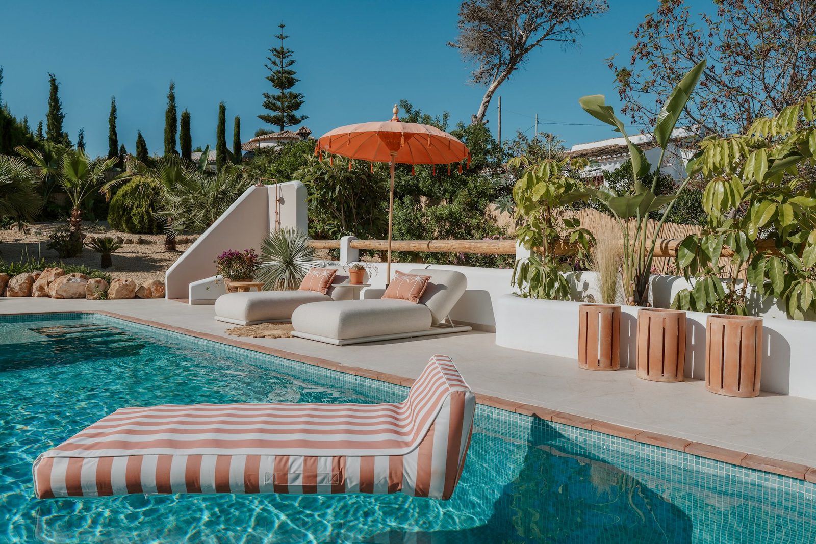 A luxurious pool area with sun loungers and a parasol at a 4-bedroom villa in Javea - The Estates