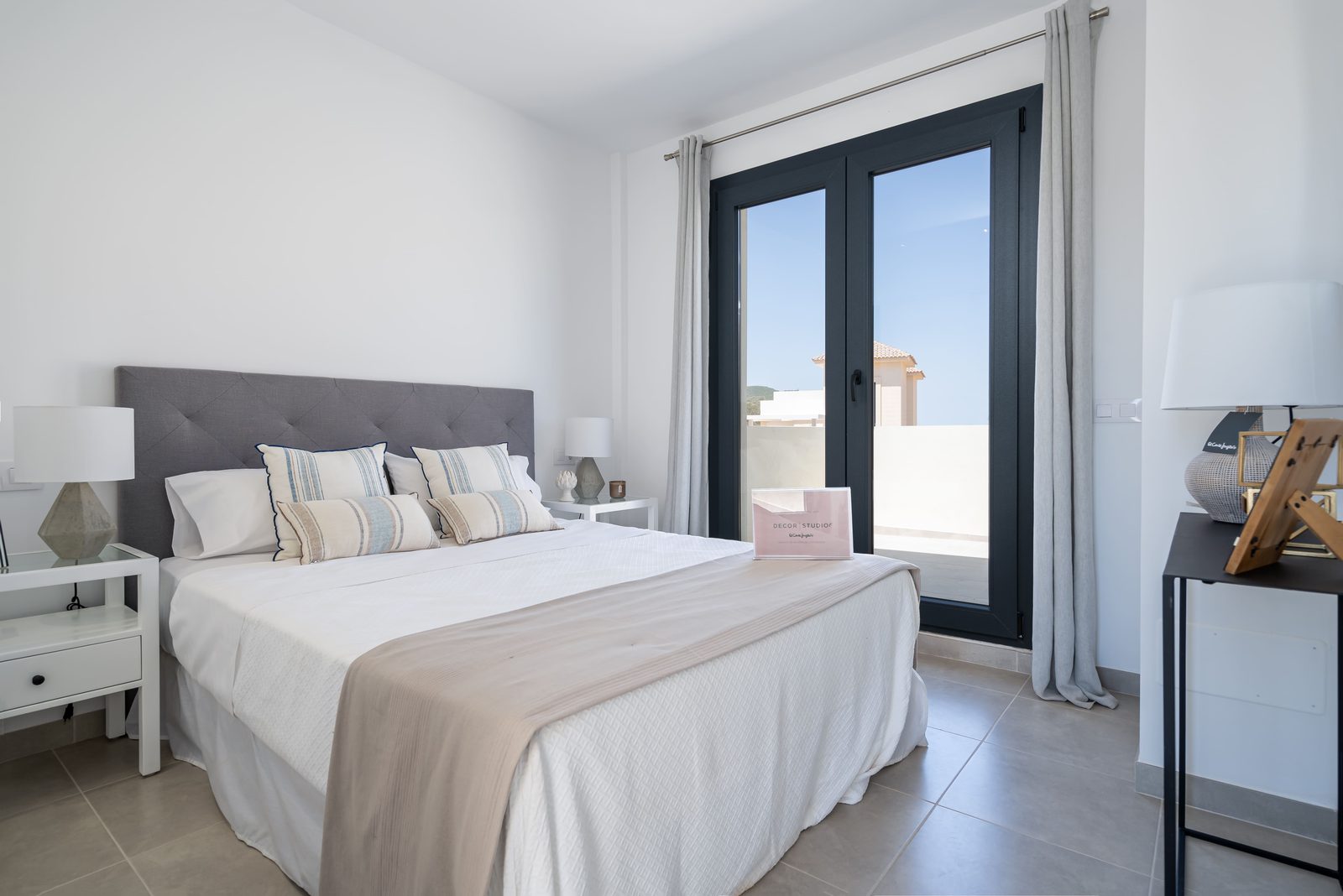 A stylish bedroom with a large window and modern furnishings in a townhouse in Manacor - The Estates