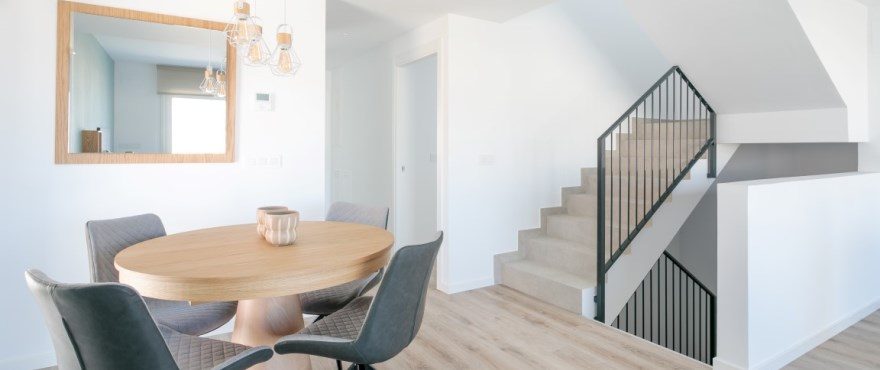 Bright dining area with round table and modern staircase of a 3-bedroom townhouse in Finestrat - The Estates
