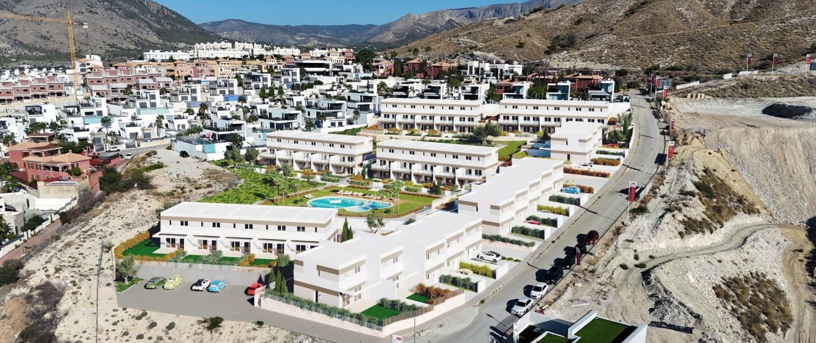 Aerial view of a modern residential development and communal pool amid mountains, featuring townhouses in Finestrat - The Estates