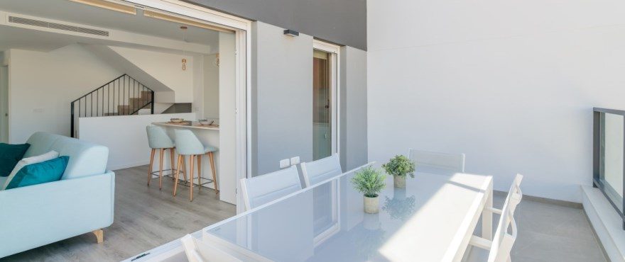 Covered terrace with outdoor dining table and open-plan living area of a