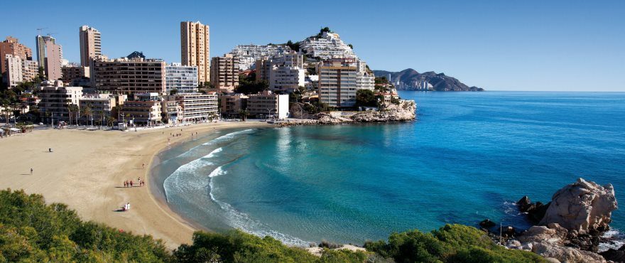 Panoramic view of a sandy beach, turquoise sea and coastal buildings of a 3-bedroom townhouse in Finestrat - The Estates