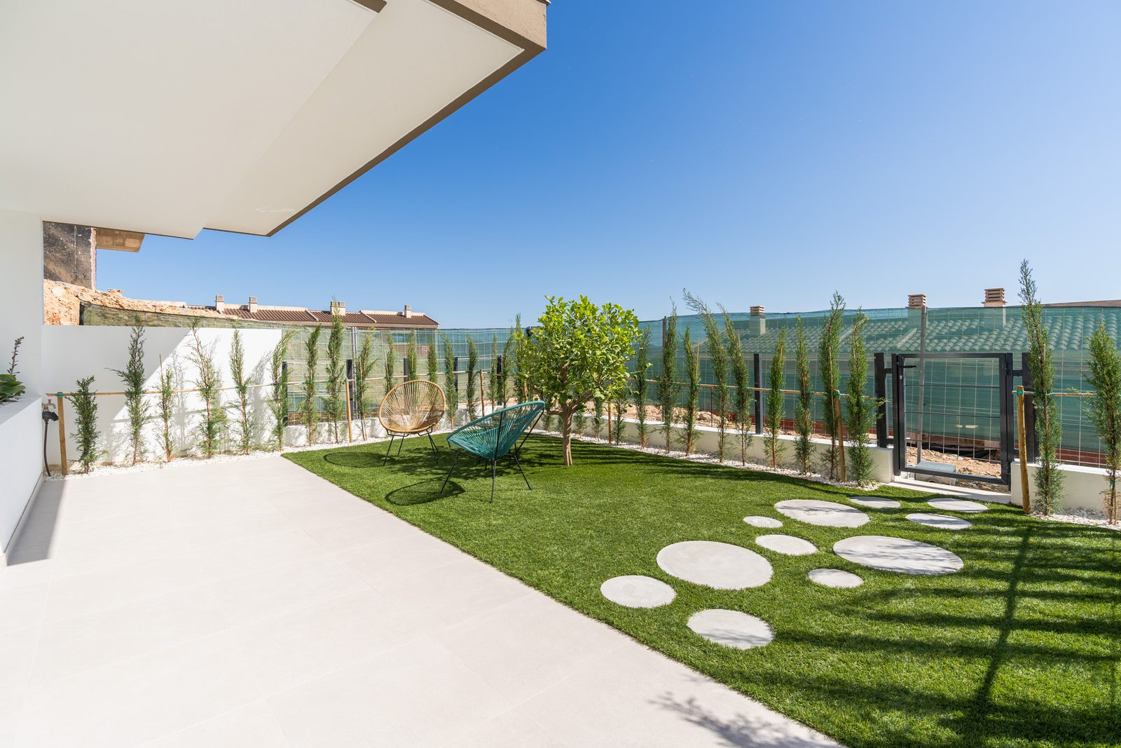 A beautifully landscaped garden with a lawn and seating area on a 4-bedroom townhouse in La Nucía - The Estates