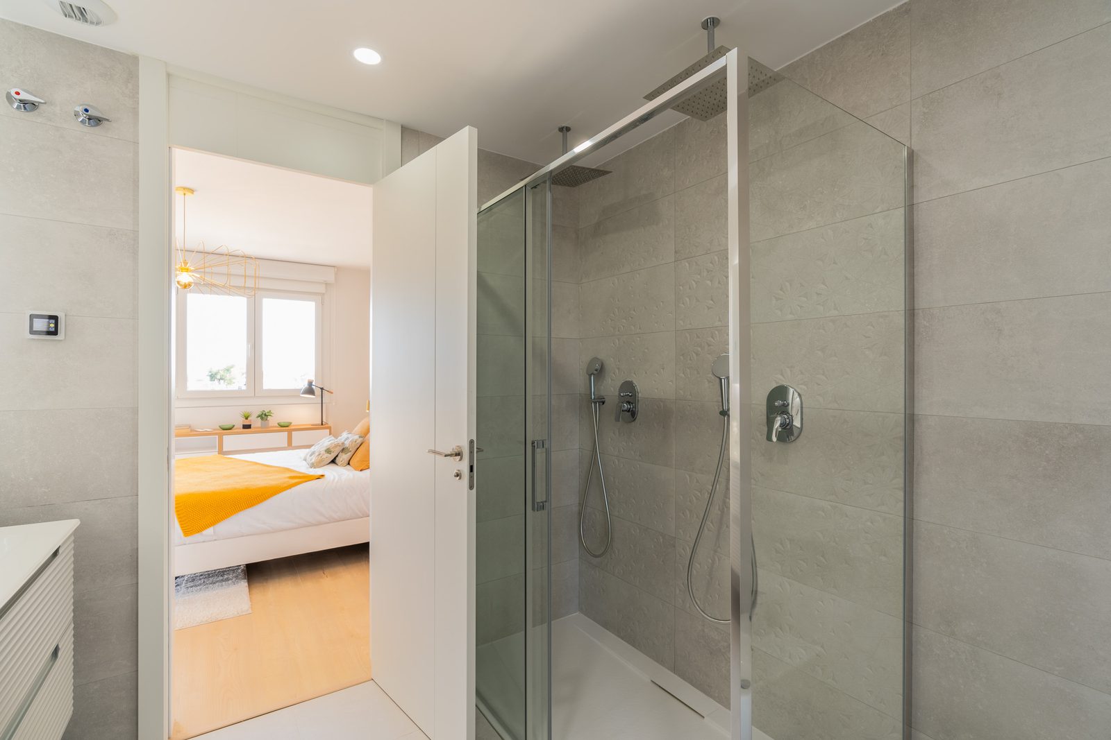 A modern bathroom with a walk-in shower and a glimpse of a bedroom in a 4-bedroom townhouse in La Nucía - The Estates