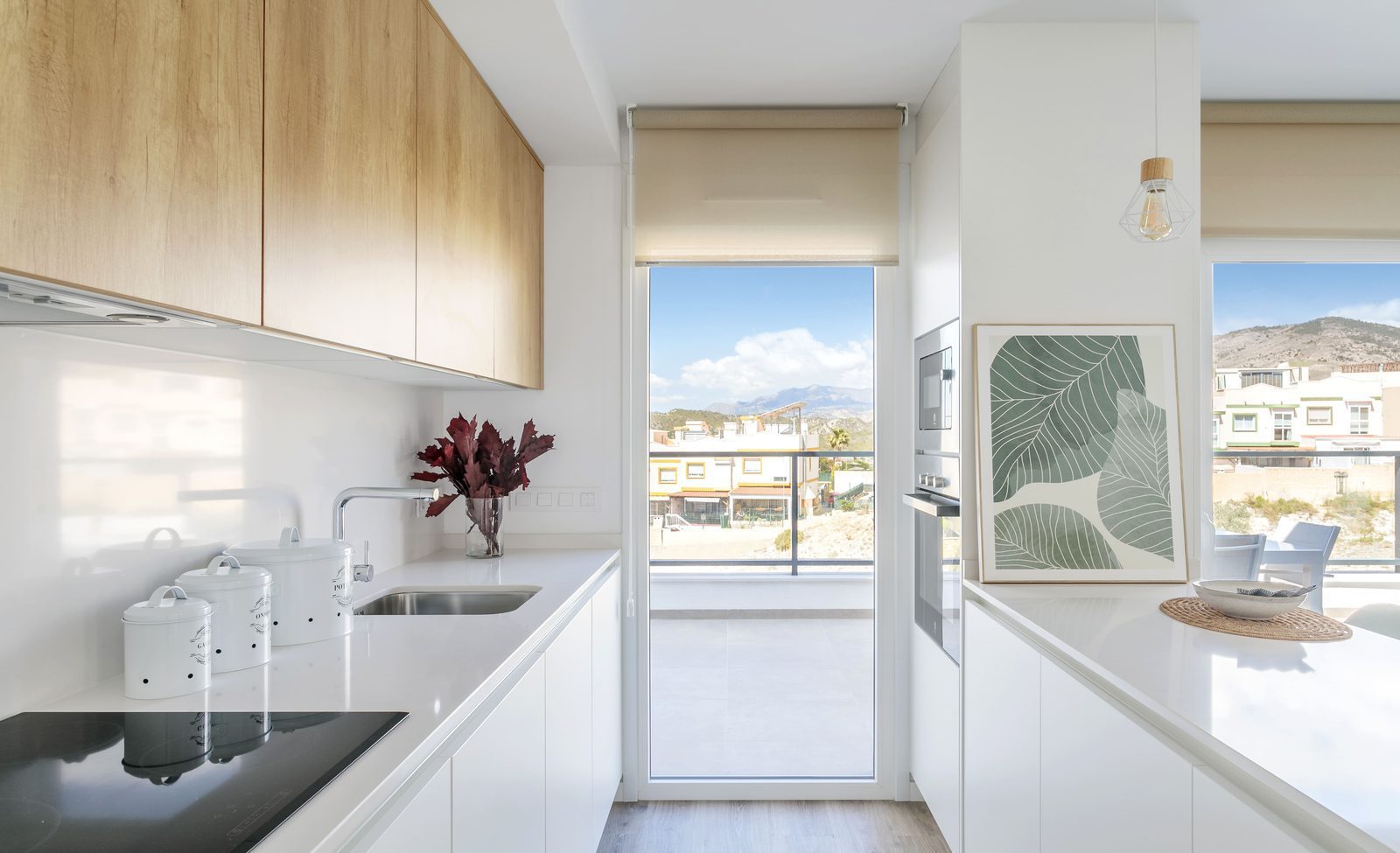 Modern kitchen with white countertops, wood cabinetry and mountain views in a 4-bedroom villa in Finestrat - The Estates