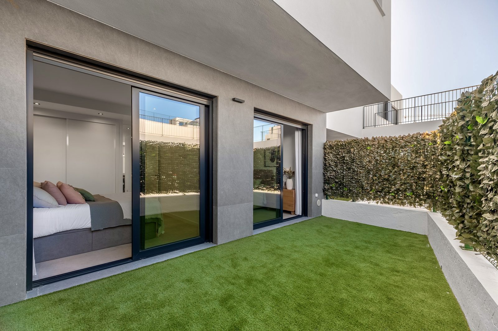 A modern bedroom with sliding doors and a private garden area in a 2-bedroom apartment in Finestrat - The Estates