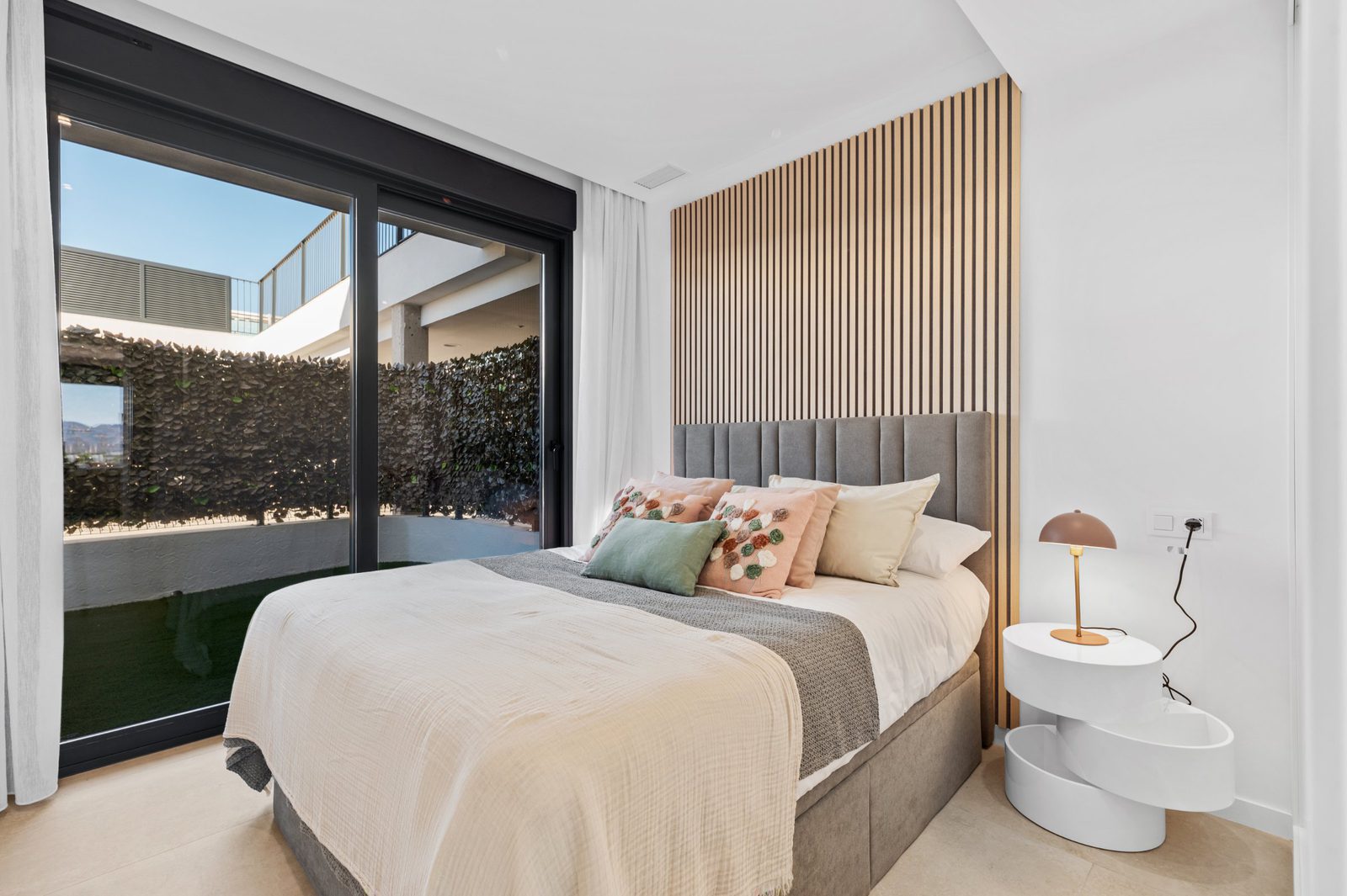A stylish bedroom with a view of the garden and sea in a 2-bedroom apartment in Finestrat - The Estates