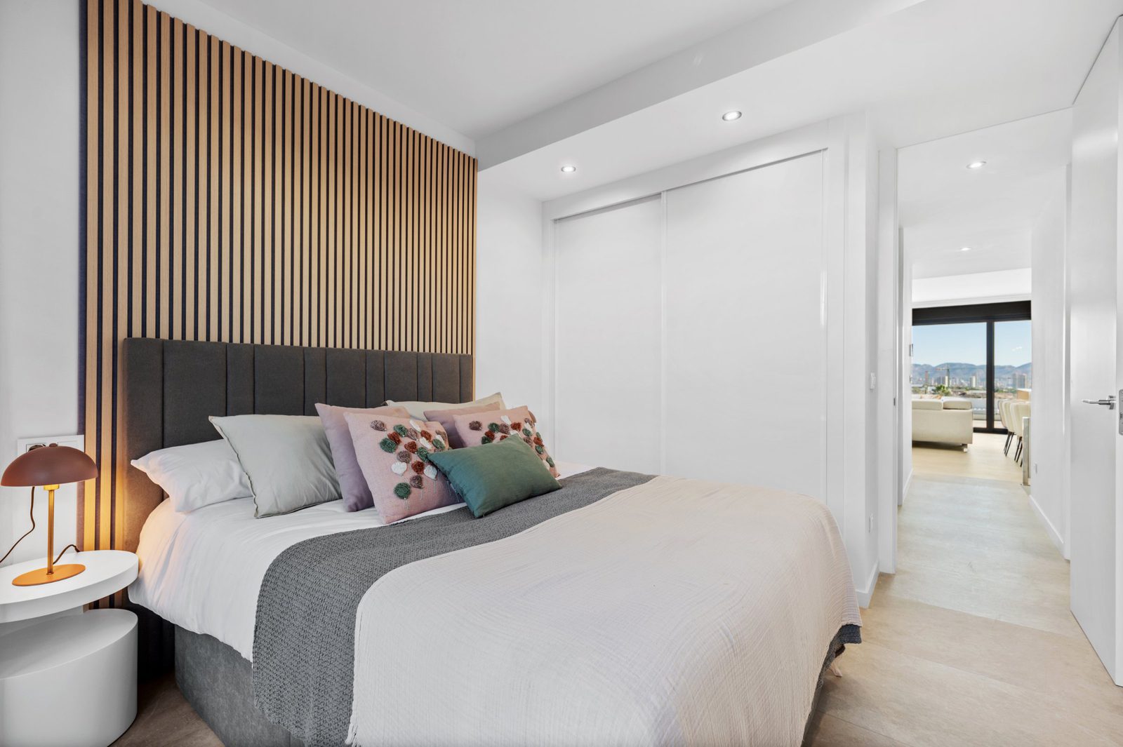 A stylish bedroom with wood paneling and views of the sea in a 2-bedroom apartment in Finestrat - The Estates