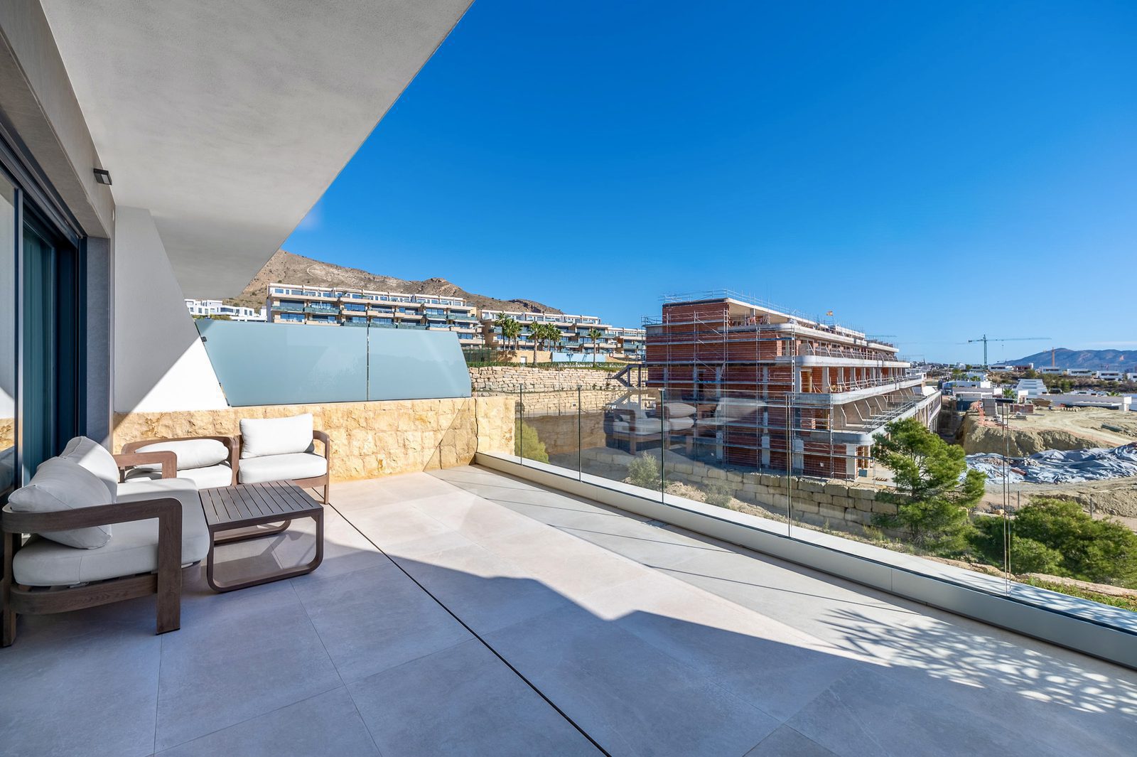 A spacious balcony with seating overlooking panoramic sea and city views of a 2-bedroom apartment in Finestrat - The Estates