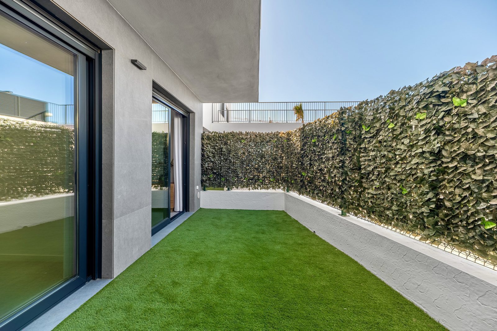 A private terrace with artificial grass and a green wall, part of a 2-bedroom apartment in Finestrat - The Estates