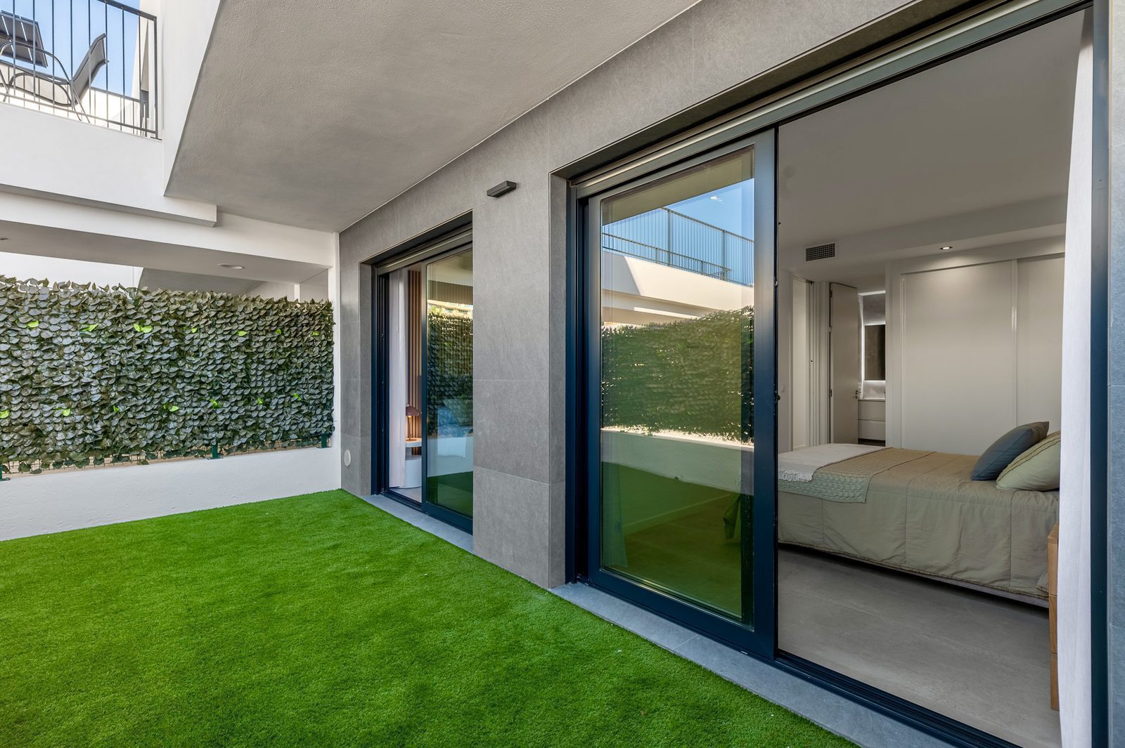 A bright bedroom with sliding doors leading to a private garden in a 2-bedroom apartment in Finestrat - The Estates