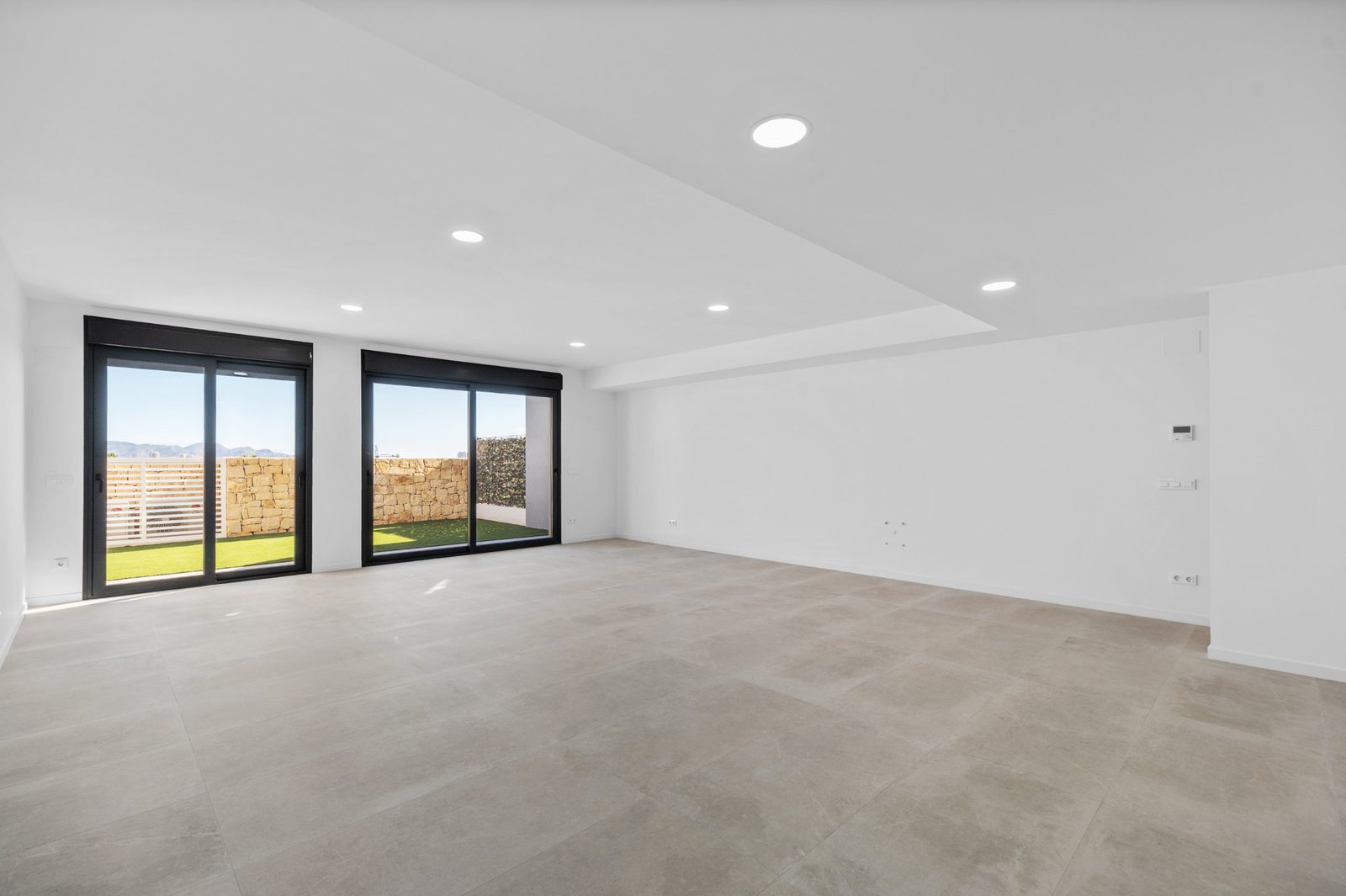 Bright living room with large windows and garden views in a 2-bedroom apartment in Finestrat - The Estates