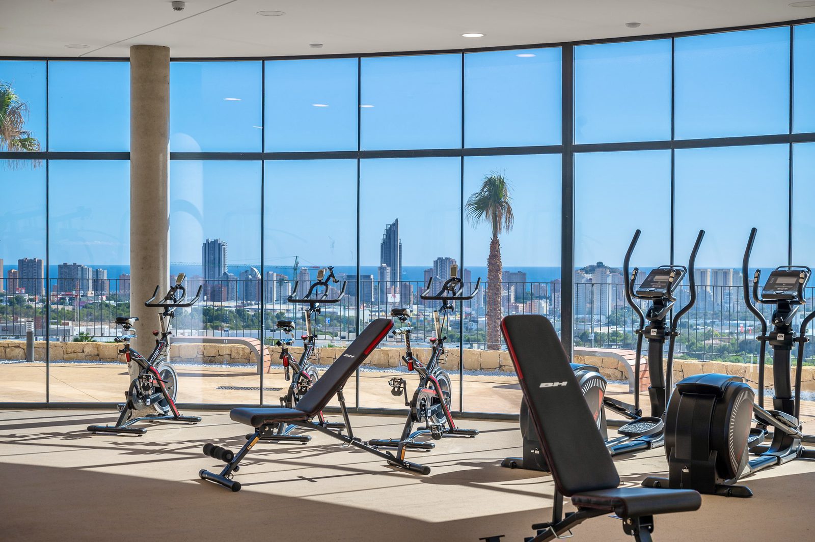 A modern gym with panoramic sea views inside a 2-bedroom apartment in Finestrat - The Estates