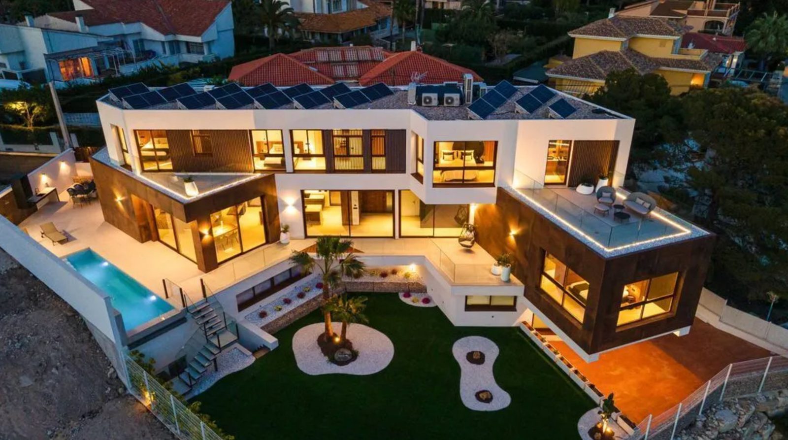 An aerial view of a modern villa with a pool and solar panels in Benidorm - The Estates