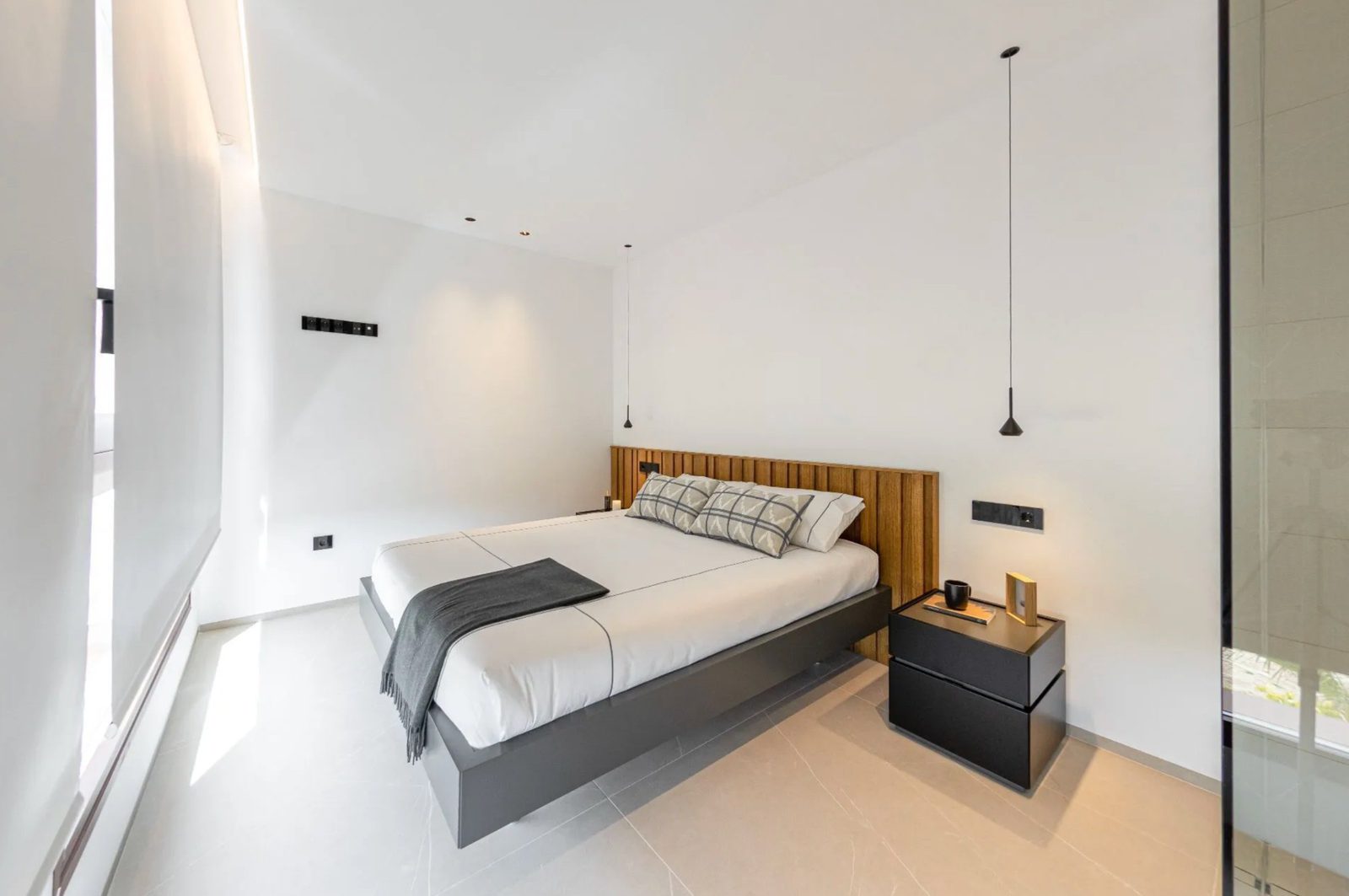 A modern bedroom with a wood-accented headboard in a 4-bedroom villa in Benidorm - The Estates