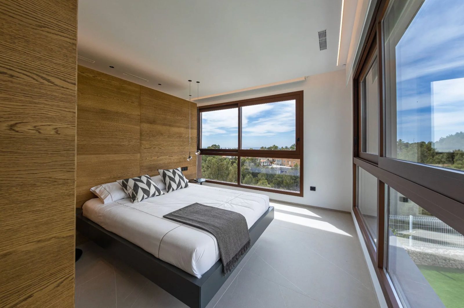 A bright bedroom with large windows overlooking sea views in a 4-bedroom villa in Benidorm - The Estates