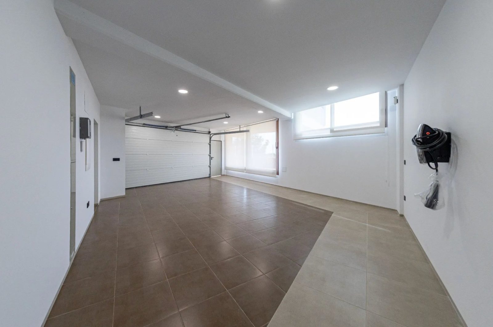 A spacious garage with tiled floors and a window in a 4-bedroom villa in Benidorm - The Estates
