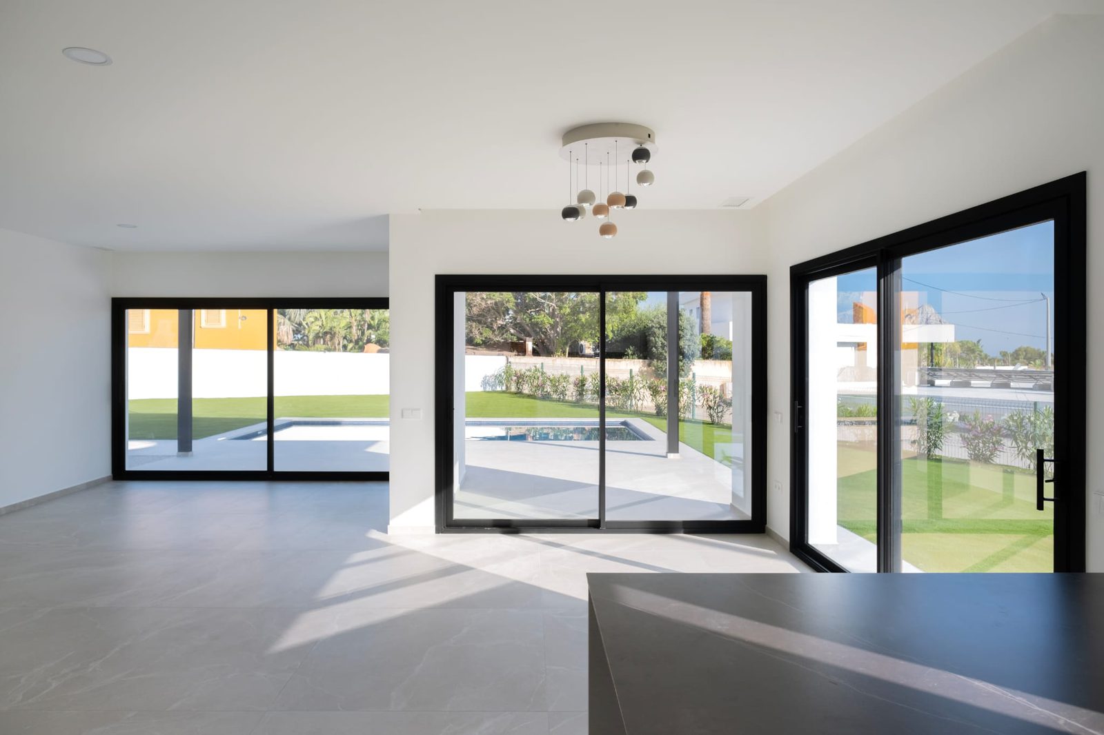 Bright living area with large windows and garden views of a 3-bedroom villa in Calpe - The Estates