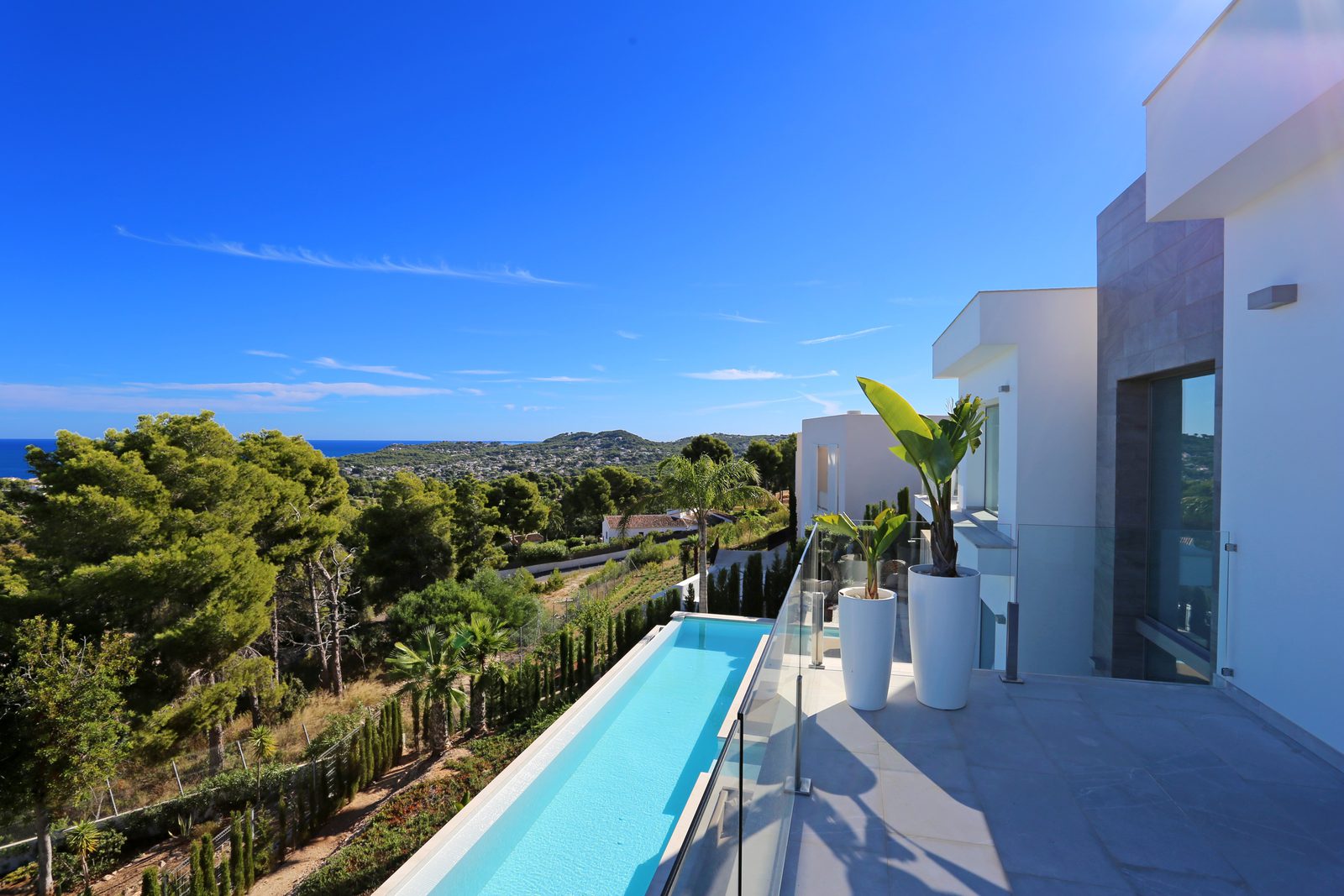 Panoramic sea views from a 4-bedroom villa in Javea, featuring a pool and lush greenery - The Estates