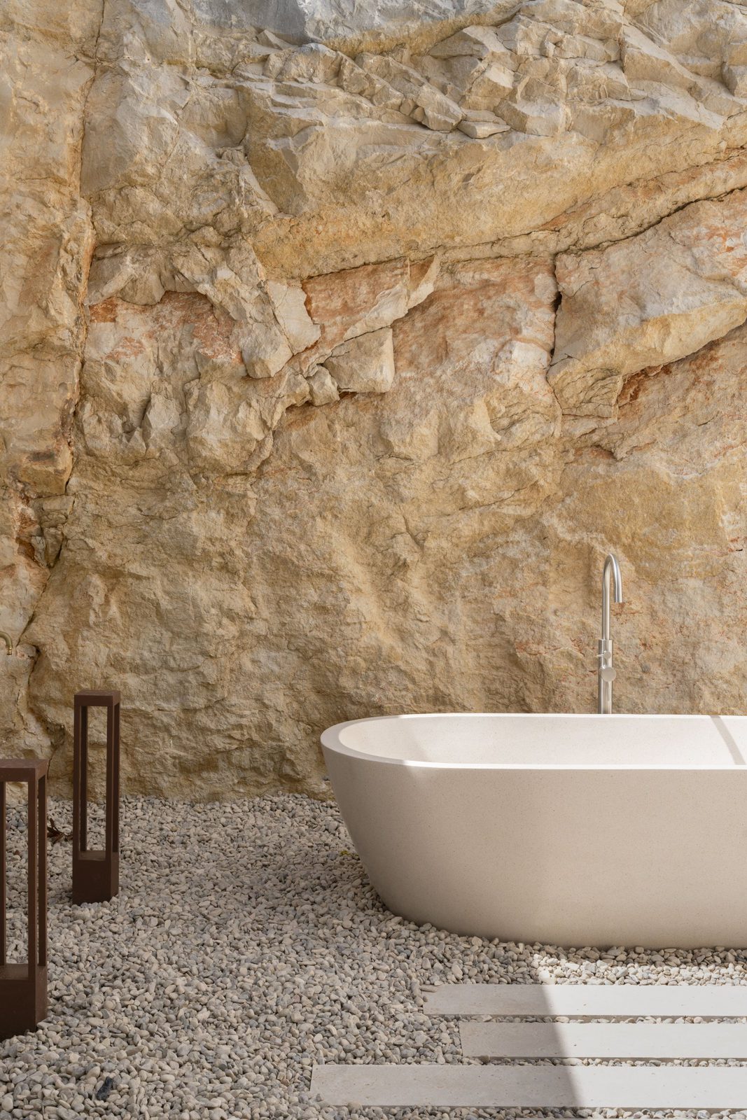 A luxurious outdoor bathtub nestled against a rocky cliff face - The Estates