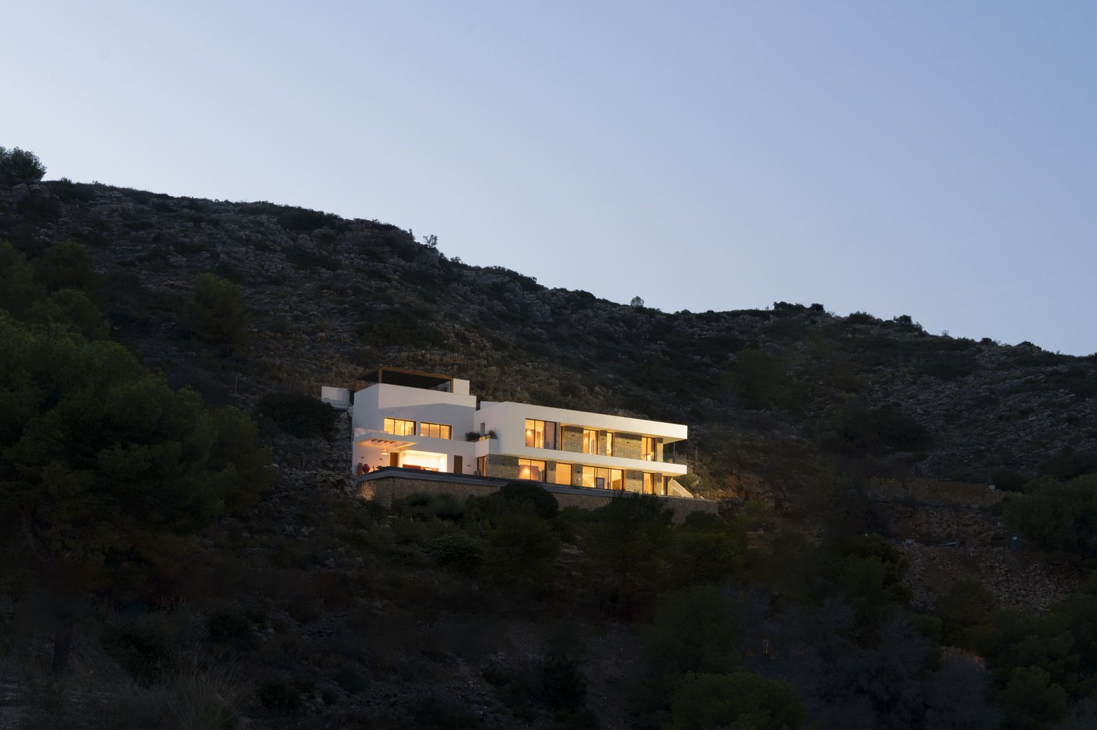 A stunning villa illuminated at dusk, nestled amongst the hills of Javea - The Estates
