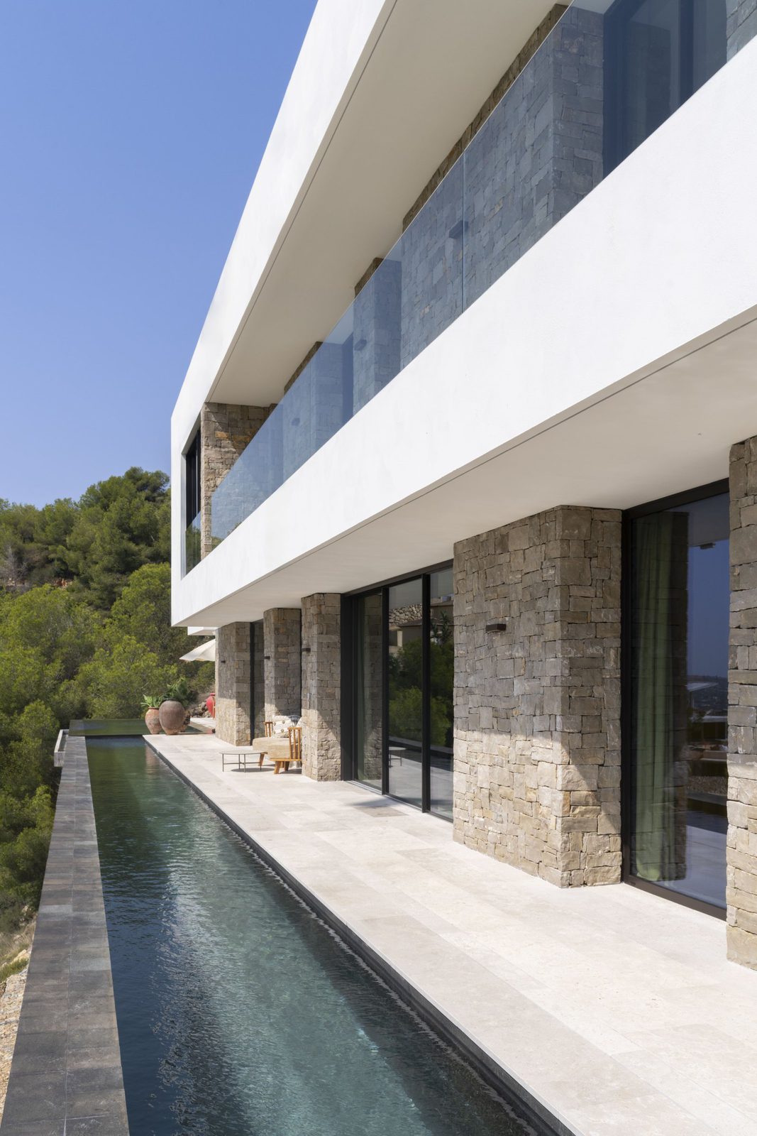 Modern villa exterior with a long pool and stunning sea, mountain, and countryside views - The Estates