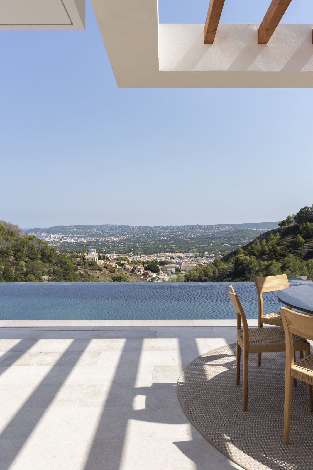 A pool and outdoor dining area with sea, mountain, and city views of a 5-bedroom villa in Javea - The Estates