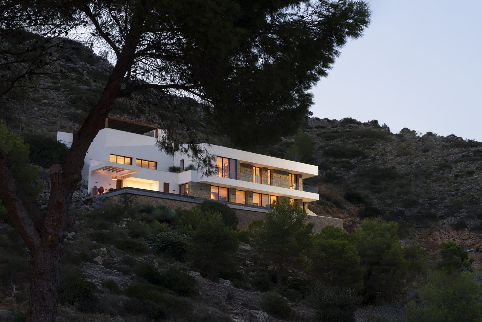 A modern villa nestled amongst pine trees and hillside vegetation in Javea - The Estates