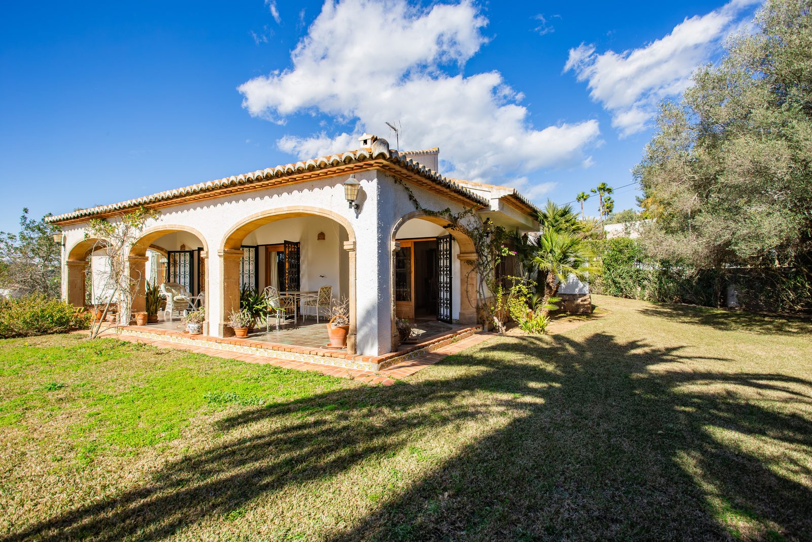 Exterior view of a 4-bedroom villa in Javea, surrounded by lush greenery and countryside - The Estates