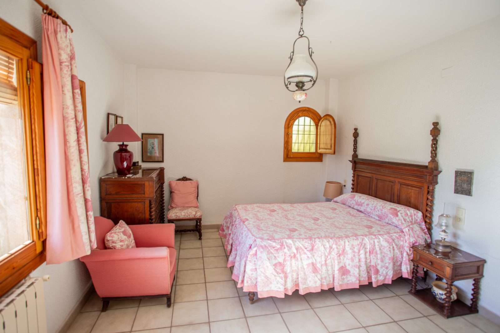 A cozy bedroom with a wooden bed and window in a 4-bedroom villa in Javea - The Estates